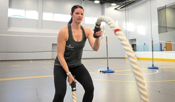 A woman exercises with large ropes.