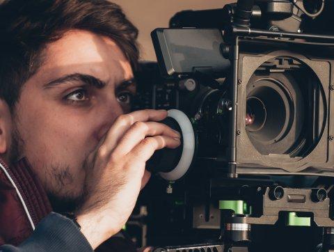 Student looks through film camera. 